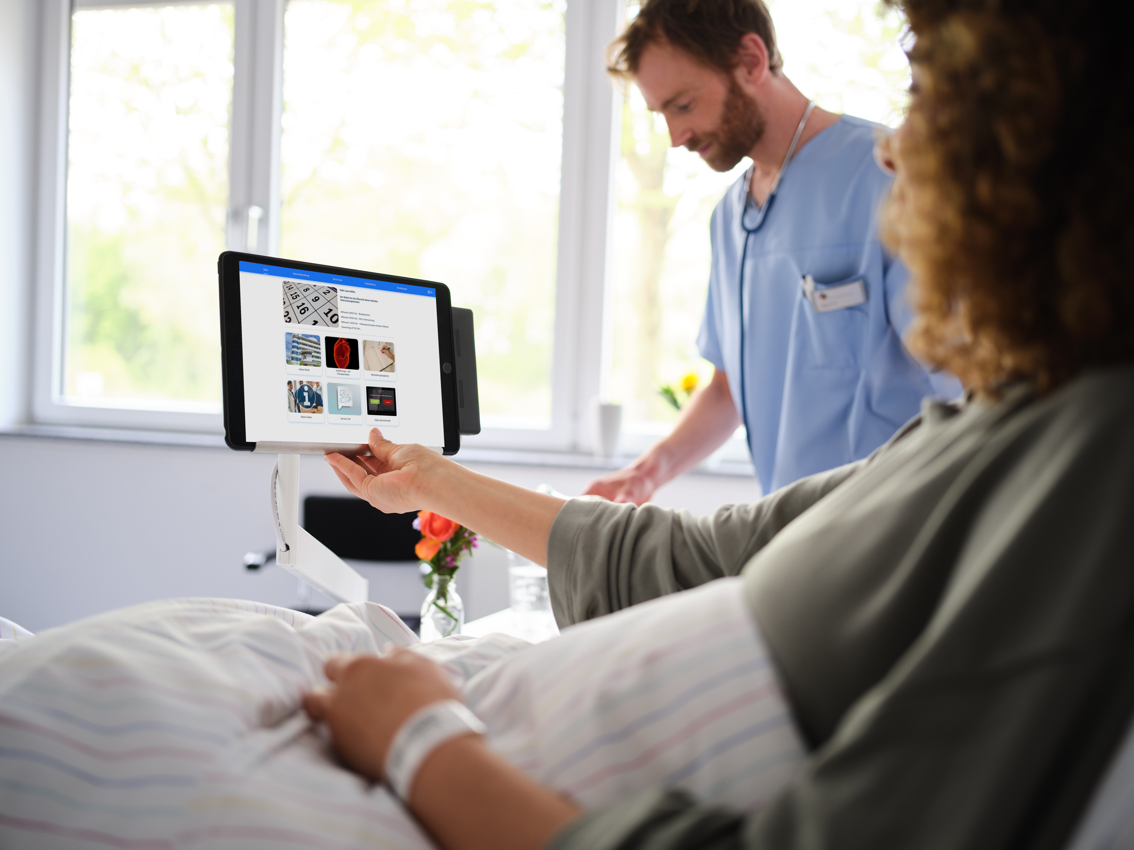 Krankenhaus digitalisieren: Patientin im Krankenhausbett bedient iPad mit eHealth Plattform BEWATEC.ConnectedCare, BEWATEC iPad-Halterung am Nachttisch
