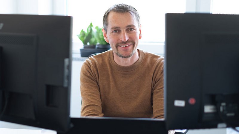 BEWATEC Projektmanager lächelnd zwischen zwei Monitoren