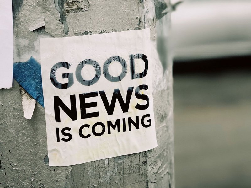Aufkleber "Good News is coming" auf Säule draußen