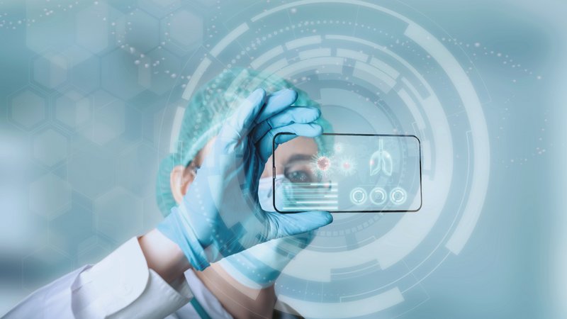 Digitalisierung Krankenhaus: Ärztin mit persönlicher Schutzausrüstung schaut auf transparentes Smartphone mit Medizindaten